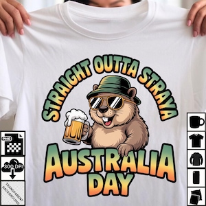 May include: White t-shirt featuring a cartoon groundhog wearing sunglasses and a hat, holding a beer mug. The shirt has the text "STRAIGHT OUTTA STRAYA" and "AUSTRALIA DAY" in a colorful design.
