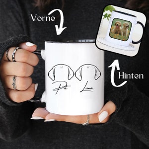 Könnte beinhalten: Eine weiße Keramiktasse mit schwarzem Innenraum und Griff. Die Vorderseite der Tasse zeigt eine schwarze Strichzeichnung von zwei Hundeohren und die Namen "Pit" und "Luna". Die Rückseite der Tasse zeigt ein Farbfoto von zwei Golden Retriever Welpen.