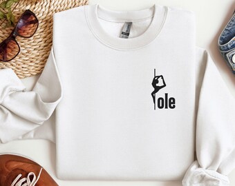 May include: White sweatshirt with a black silhouette of a person on a pole with the word "ole" printed below.