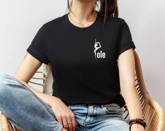 May include: Black t-shirt with a white graphic of a person on a pole and the word "Yole" in white. The shirt has short sleeves and a crew neck.