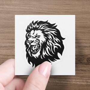 May include: Black and white illustration of a roaring lion's head with a detailed mane.