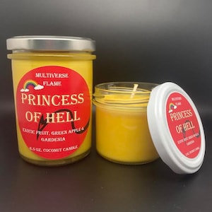 May include: Two yellow coconut candles in glass jars with silver lids. The labels are red with black text and a rainbow graphic. The text on the labels reads "MULTIVERSE FLAME PRINCESS OF HELL EXOTIC FRUIT, GREEN APPLE & GARDENIA 6.5 OZ. COCONUT CANDLE".