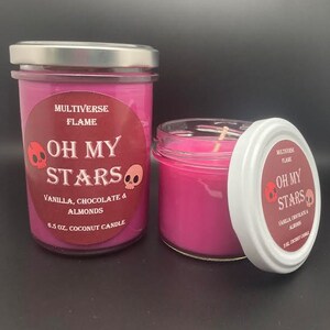 May include: Two pink coconut wax candles with a skull and crossbones design and the text "Oh My Stars" on the label. The candles are labeled "Vanilla, Chocolate & Almonds" and are 6.5 oz.