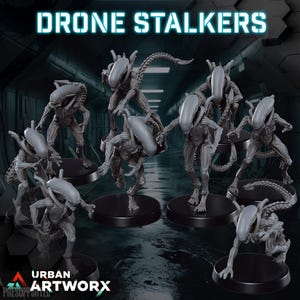 Peut inclure: Un ensemble de huit figurines grises d'extraterrestres, chacune avec une pose unique, debout sur des bases circulaires noires. Les figurines sont étiquetées "Drone Stalkers" et "Urban Artworx".