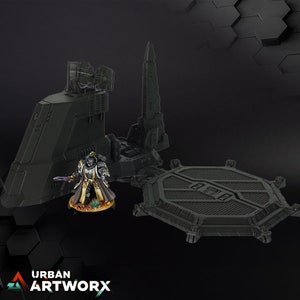 Könnte beinhalten: Ein schwarzes und graues Raumschiffmodell mit einer sechseckigen Landeplattform. Eine Miniaturfigur eines Raumkriegers in goldener und schwarzer Rüstung steht auf der Landeplattform.