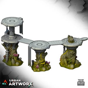 Op de afbeelding: Een miniatuur sci-fi terreinset met drie verhoogde cirkelvormige platforms verbonden door loopbruggen. De structuren worden ondersteund door organische, boomachtige basissen in groen- en bruintinten, geaccentueerd met kleine kristallen en planten.