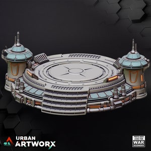 Op de afbeelding: Een cirkelvormig, grijs, sciencefiction-themaplatform met twee torens. De torens zijn teal en wit met oranje accenten. Het platform heeft een centraal cirkelvormig gebied met een verhoogde rand en een kleinere cirkel in het midden. Het platform is ontworpen voor gebruik in tabletop-spellen.
