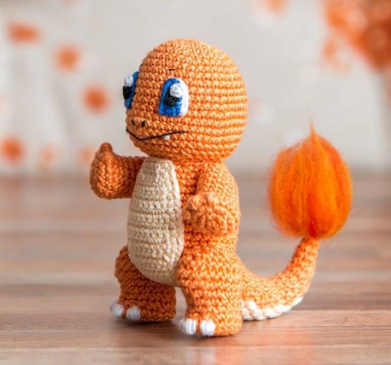 May include: A crocheted orange and white plush toy resembling a fire-type Pokemon with a fluffy orange tail.