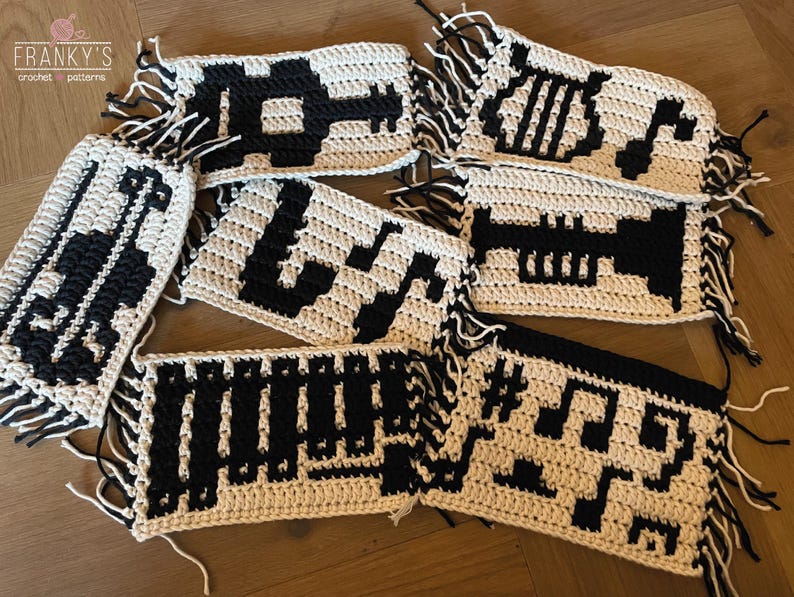 May include: Crochet patterns for musical notes, a trumpet, and a treble clef. The patterns are made with white yarn and black yarn. The patterns are fringed on the edges.