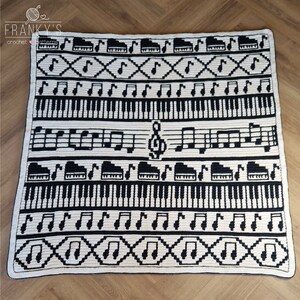 May include: Black and white crochet blanket with a musical theme. The blanket features musical notes, piano keys, and a treble clef.