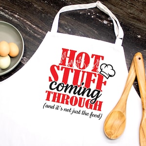 May include: White apron with the text "HOT STUFF COMING THROUGH (and it's not just the food)" in red and black. The words "HOT STUFF" have flames as part of the design. A chef's hat is next to the word "THROUGH".