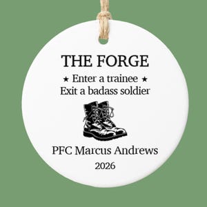 May include: White ceramic ornament with the text "THE FORGE" and "★ Enter a trainee ★ Exit a badass soldier". Below is a graphic of combat boots and the text "PFC Marcus Andrews 2026". A jute twine loop is at the top.