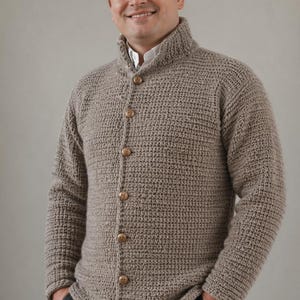 May include: A light brown, button-down cardigan sweater with a textured knit pattern. The sweater has a high collar and wooden buttons. The person in the image is wearing a gray tweed cap and a white collared shirt.