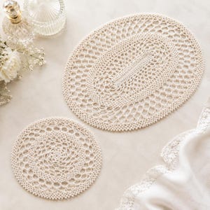 May include: An off-white crochet doily set consisting of one large oval piece and one smaller circular piece. Both items feature an intricate, openwork mesh pattern with a delicate, repeating knotted stitch design throughout the entire surface.