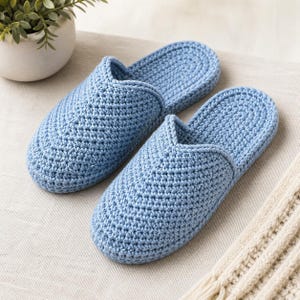 May include: A pair of light blue crochet slippers. The slippers are made of a soft, textured yarn and have a closed-toe design. The slippers are approximately 10 inches long.