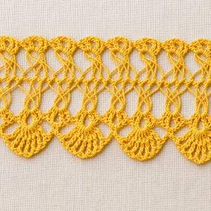 May include: A vibrant yellow crochet lace trim featuring a repeating fan-shaped pattern along the bottom edge. The design consists of intricate openwork loops and interconnected stitches that create a delicate, scalloped border effect throughout.