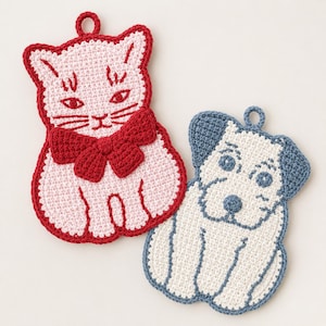 May include: Two crocheted potholders shaped like animals. One is a light pink cat with a dark red bow and red outline. The other is a white dog with blue ears, a blue nose, and a blue outline. Both have a small loop at the top for hanging.