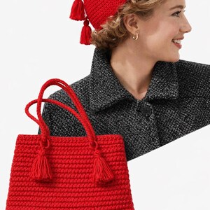 Puede incluir: Un bolso de mano rojo tejido a ganchillo con borlas y asas a juego, combinado con un gorro rojo tejido a ganchillo con borlas. El gorro y el bolso est&aacute;n hechos de un hilo texturizado, creando un conjunto cohesivo. El bolso es rectangular.