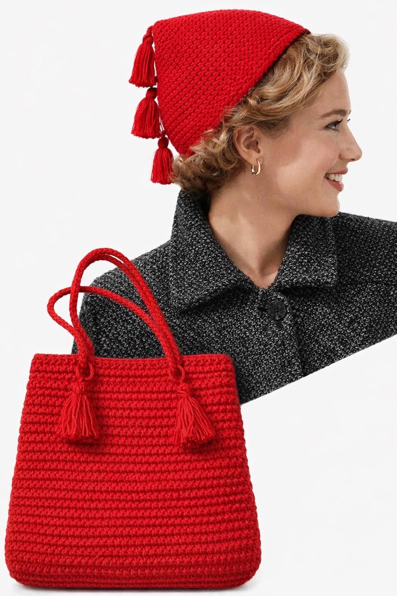 Puede incluir: Un bolso de mano rojo tejido a ganchillo con borlas y asas a juego, combinado con un gorro rojo tejido a ganchillo con borlas. El gorro y el bolso est&aacute;n hechos de un hilo texturizado, creando un conjunto cohesivo. El bolso es rectangular.