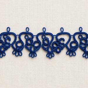 May include: A continuous strip of deep blue tatting lace featuring a repeating pattern of interconnected loops and circular motifs. The lace trim has a scalloped edge with small, delicate loops extending from the top and bottom borders.