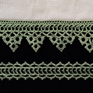 May include: Two rows of sage green lace trim against a black background. The top row has a scalloped edge with circular and diamond-shaped elements. The bottom row is a simpler, repeating pattern. A light beige fabric is at the top.