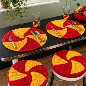 May include: A set of round, crocheted placemats and matching stool covers featuring a vibrant red and yellow spiral pattern. The set includes two circular placemats, two matching glass sleeves, and two round stool cushions, all with a consistent design.