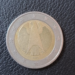 Peut inclure: Une pièce de 1 euro argentée et dorée représentant l'aigle fédéral allemand avec l'année 2002 inscrite en bas.