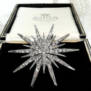 May include: A silver starburst brooch, studded with clear crystals, presented in a black velvet box. The box features the text "142 JAYS 144 OXFORD ST. LONDON, W. DIAMOND MERCHANTS. Estd. 1790".