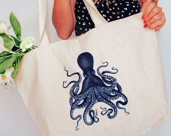 May include: A white canvas tote bag with a blue octopus illustration. The bag has two long straps and is being held by a person.