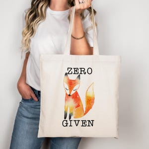 May include: A white canvas tote bag with a watercolor illustration of a fox and the text "ZERO GIVEN".