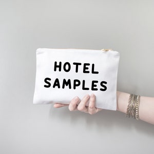 May include: White canvas pouch with a zipper closure. The pouch has black text that reads "HOTEL SAMPLES".