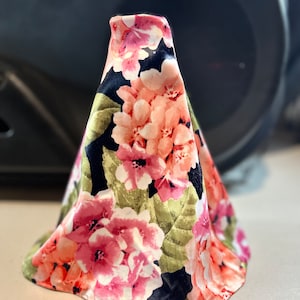 May include: A floral patterned gear shift boot with pink, white, and green flowers on a black background.
