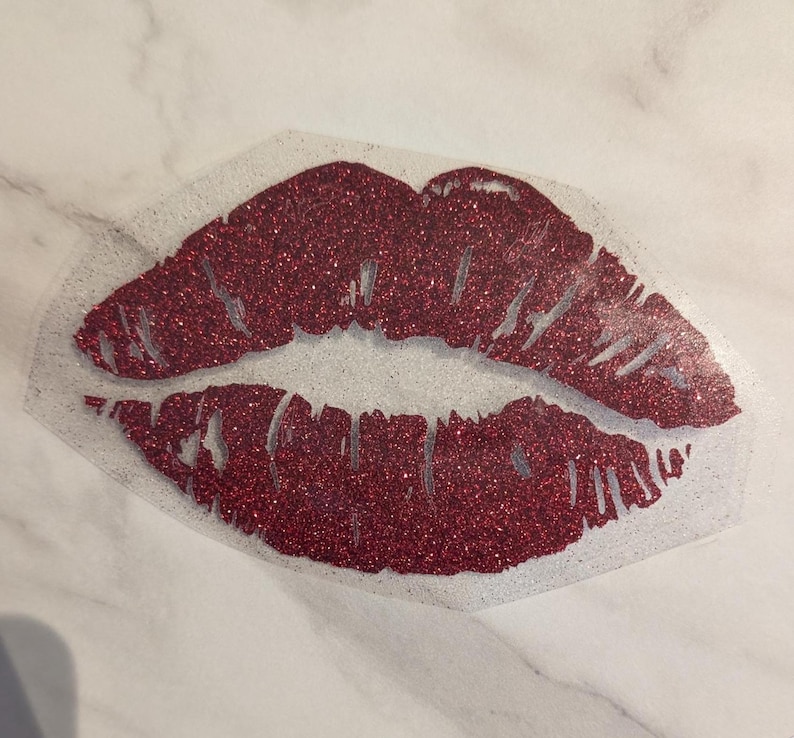 Puede incluir: Un dise&ntilde;o de labios rojos con purpurina sobre un fondo transparente. Los labios son de color rojo intenso y est&aacute;n llenos de purpurina. El dise&ntilde;o es probablemente para manualidades o decoraci&oacute;n de ropa.