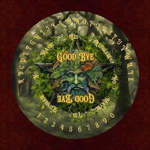 May include: A circular spirit board featuring a central green face composed of leaves and branches. The board displays the alphabet, numbers zero through nine, and the words YES, NO, MAYBE, REPHRASE, and GOOD BYE in a yellow serif font.
