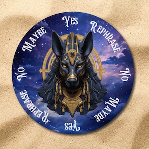 May include: Circular divination board with a depiction of Anubis, adorned with gold details, set against a backdrop of a starry night. The board displays the words "Yes", "No", "Maybe", and "Rephrase".