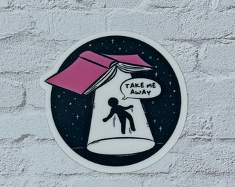 May include: A black and white sticker with a pink book flying in the air like a UFO. A stick figure is falling into the book with the words "Take Me Away" in a speech bubble.