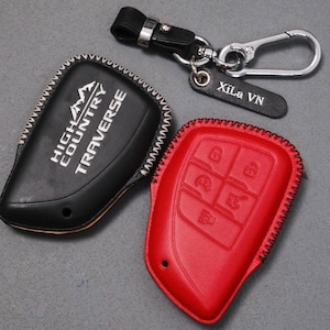 May include: A black leather key fob cover with "HIGH COUNTRY TRAVERSE" in white lettering, and a red leather key fob cover with embossed buttons. A keychain with a leather tag that says "Xila VN" is also included.