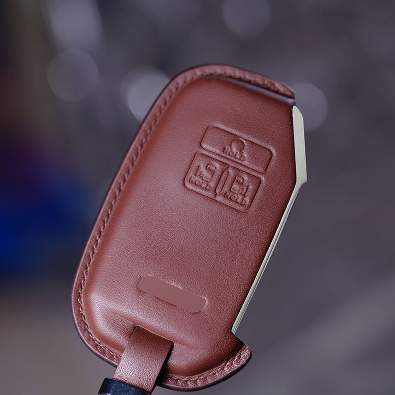 May include: A brown leather key fob with a silver metal key ring. The fob has three buttons labeled "HOLD", "HOLD", and "HOLD".