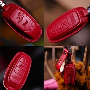 May include: A set of four images showcasing a red leather key fob cover. The cover features embossed buttons and the word "Kandi" on the fob and strap. The apple logo is also embossed on the fob.