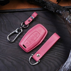 May include: Pink leather key fob with a silver key ring and a matching pink leather strap. The key fob has four buttons and a silver metal loop.