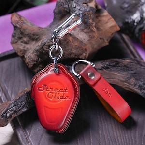 May include: Red leather key chain with a silver key ring and a red leather key fob with the words "Street Glide" embossed on it. The key fob has a silver ring and a small silver tag with the word "Jan" embossed on it.