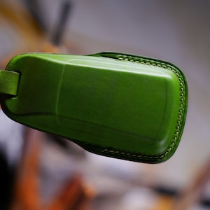 May include: A green leather key fob with a stitched edge.