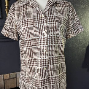 May include: A white and brown short-sleeved button-up shirt with a houndstooth pattern.
