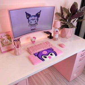 May include: A pink computer setup featuring a curved monitor displaying a Kuromi character, a pink mechanical keyboard, a plush Kuromi wrist rest, a pink mouse, a Hello Kitty figurine, a pink desk lamp, and a potted plant on a white desk.