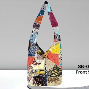 Peut inclure: Un sac à bandoulière en patchwork coloré avec une longue bandoulière. Le sac est fait de différents tissus et motifs, notamment des motifs floraux, géométriques et paisley. Le sac est un mélange vibrant de couleurs, notamment le rouge, l'orange, le jaune, le vert, le bleu et le violet. Le sac est étiqueté "SB-006 Face avant".