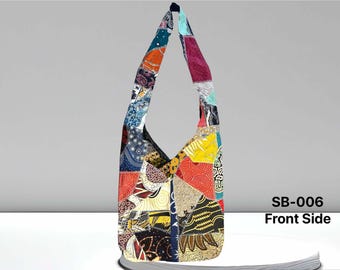 Pode incluir: Uma bolsa de ombro de patchwork colorida com uma alça longa. A bolsa é feita de diferentes tecidos e padrões, incluindo desenhos florais, geométricos e paisley. A bolsa é uma mistura vibrante de cores, incluindo vermelho, laranja, amarelo, verde, azul e roxo. A bolsa é etiquetada como "SB-006 Lado frontal".