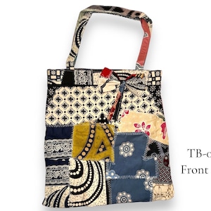 May include: A patchwork tote bag featuring a variety of colourful fabrics and patterns. The bag has two handles and a front pocket. The text "TB-006 Front side" is printed on the bottom right corner of the bag.