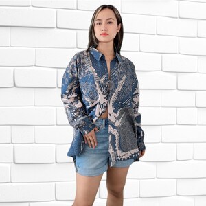 May include: A blue and white patterned long-sleeved shirt with a collared neckline and button fastening. The shirt is loose-fitting and has a relaxed silhouette.