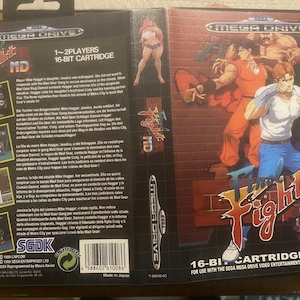 Può includere: Una cartuccia di gioco Sega Mega Drive per il gioco "Mad Fight" con uno schema di colori rosso, bianco e blu. Il gioco è una cartuccia a 16 bit ed è per 1-2 giocatori.