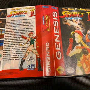 May include: A Sega Genesis game cartridge for Streets of Rage 2. The game features a red, white, and blue colour scheme with a picture of a female character in a green outfit. The text "The New Challengers" is printed on the front of the cartridge.